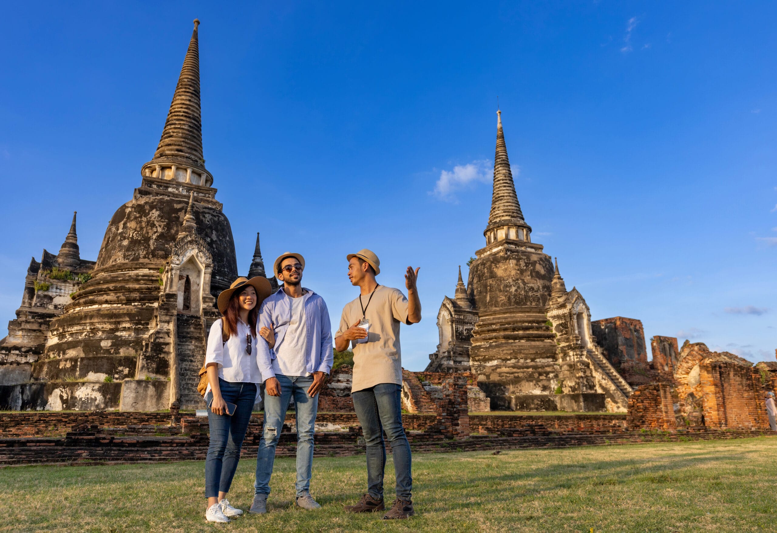 Thai local tour guide is explaining the history of old Siam to the couple of tourist on their backpacker honeymoon travel to ancient temple of Ayutthaya, Thailand Why Choose I See Adventures travel agency
