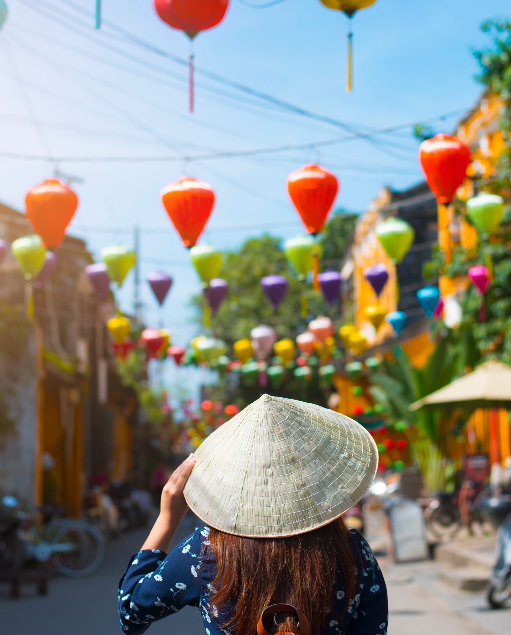 Tourist is walking in Old town in Hoi An, Vietnam. back view of young woman wearing the traditional Vietnamese straw hat looking at the street of Hoi An