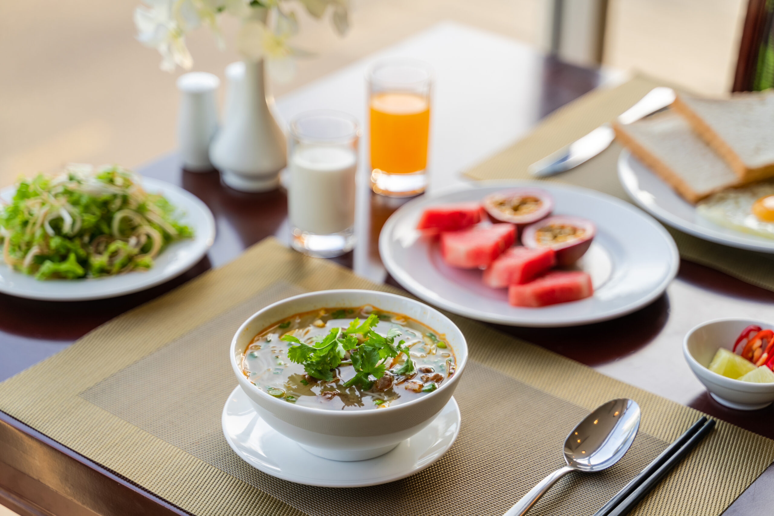 asian-style breakfast with soup, salad, fruits, and toast