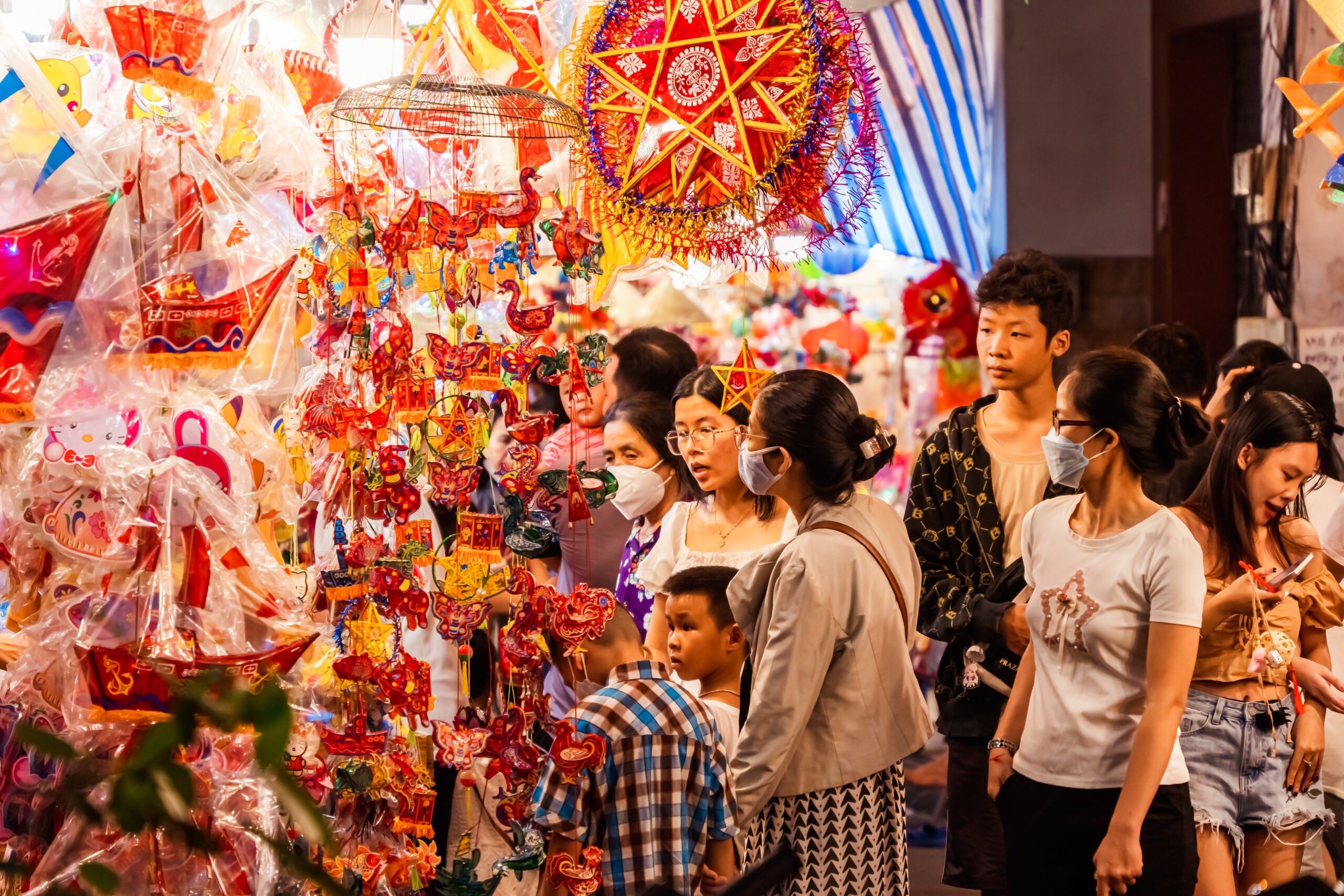 night view of family viewing toys sold by vendor on a busy street