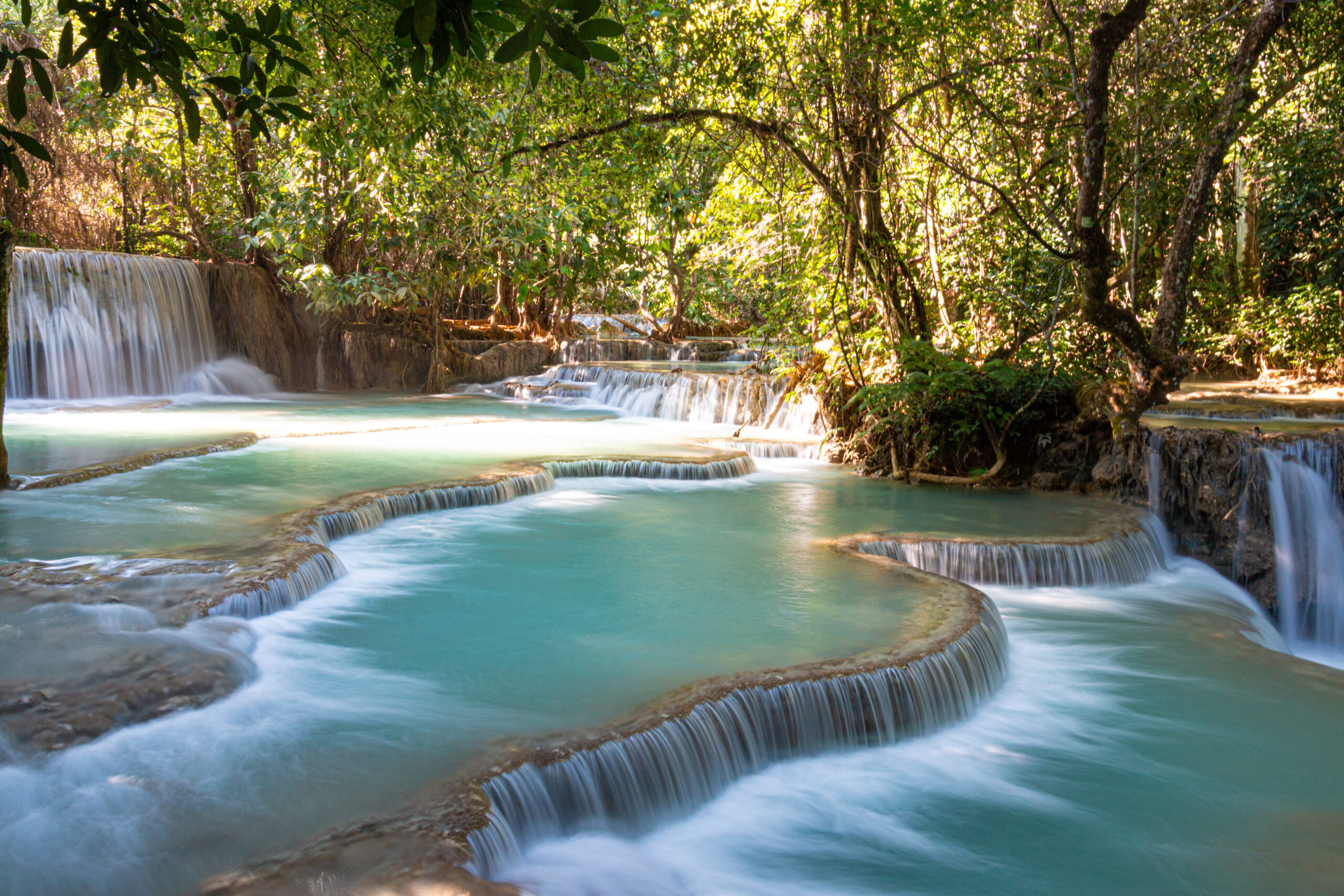 waterfall flows into turquoise pools and natural terraces at Kuang Si Falls, Laos