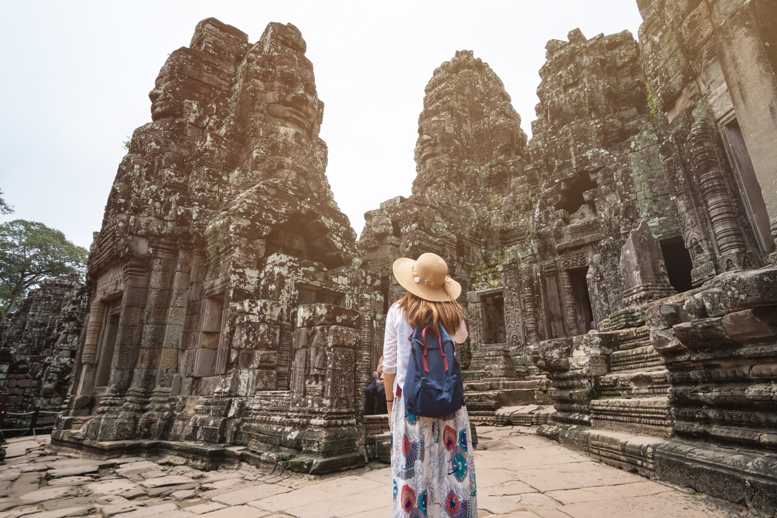 Young woman traveler visiting in Bayon temple at Angkor Wat complex, Khmer architecture heritage in Siem Reap, Cambodia Southeast Asia travel agency