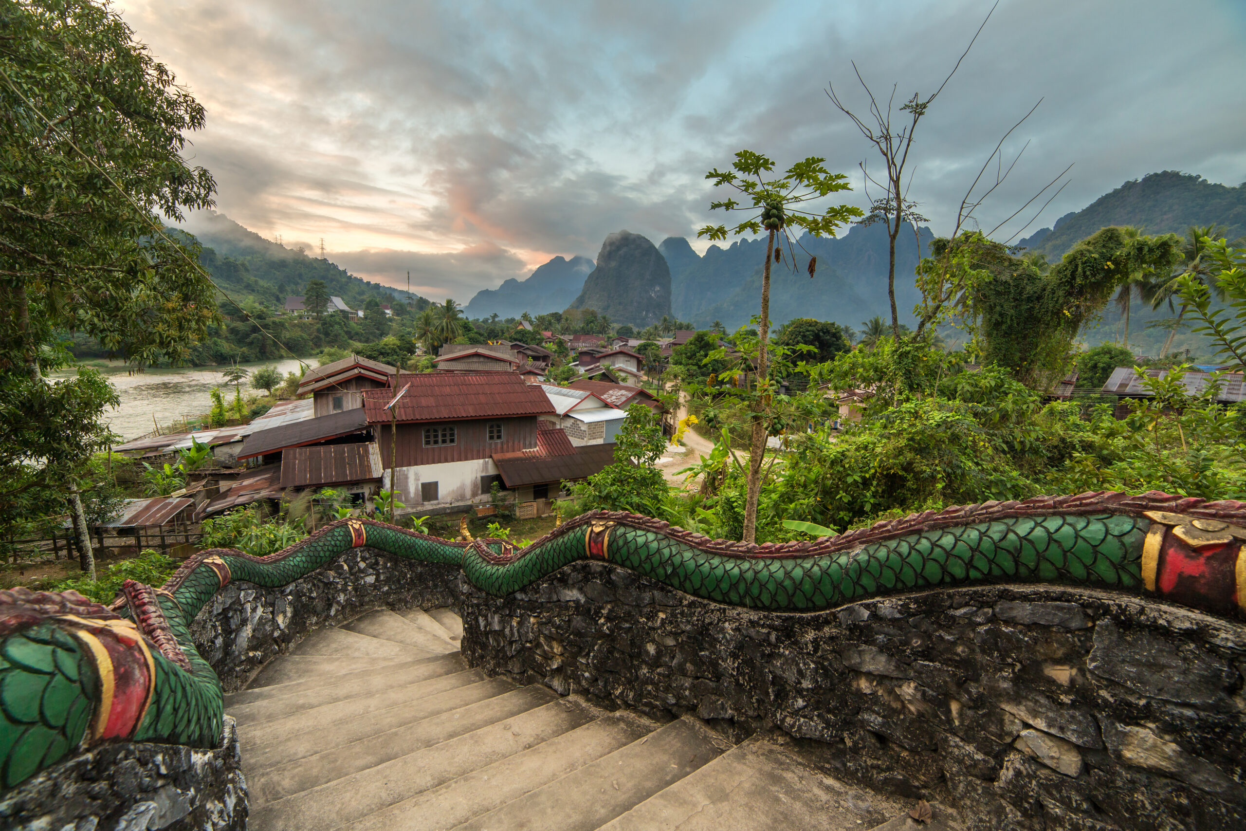Traditional lao village with temple stairs and mountain background near Vang Vieng, Laos